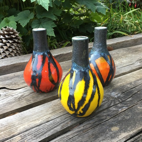brightly coloured handmade ceramic pots with black drip detailing around the neck, vase is bulb shaped